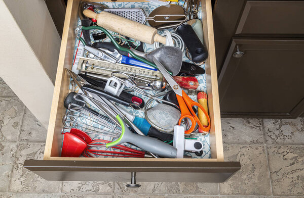 A genuine kitchen junk drawer almost overflowing with genuine kitchen junk.
