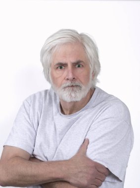 Vertical shot of an angry looking old man with white hair on a white background. Standing from the waist up.