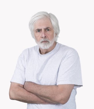 Vertical shot of an angry old man with white hair with his arms crossed on a white background. Standing from the waist up.