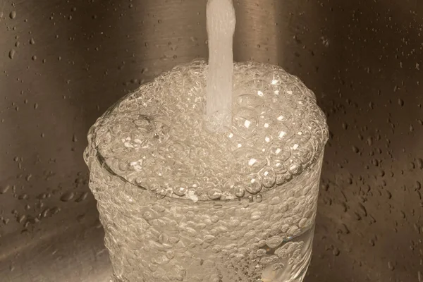 Close-up photo of water overflowing a drinking glass.