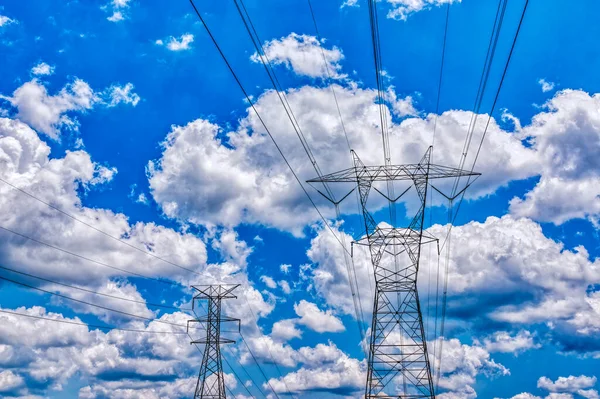 Poziome Ujęcie Głównych Wież Elektrycznych Przeciwko Puszystym Białym Chmurom Niebieskim — Zdjęcie stockowe
