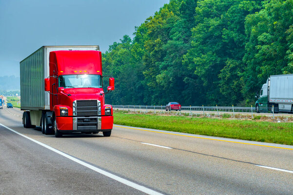 Horizontal shot of a modern red semi truck on the interstate highway.