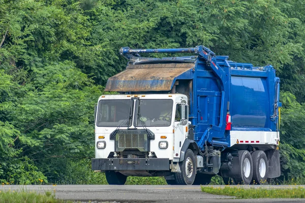 公路上一辆蓝白相间的垃圾车的横向拍摄 图库图片