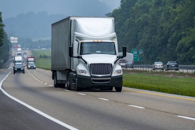 Tennessee otobanı boyunca giden büyük, beyaz, 18 tekerlekli bir aracın yatay görüntüsü..