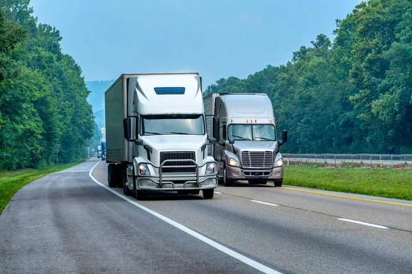 軽トラフィックで州間高速道路の2台のセミトラックの水平撮影 ロイヤリティフリーのストック画像