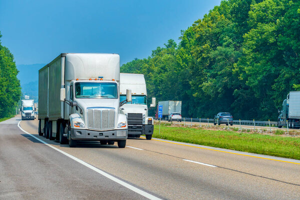 Horizontal shot of three white semis on the interstate with copy space.