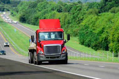 Eyaletler arası otobanda fotokopi alanı olan kırmızı bir kamyonun yatay görüntüsü..