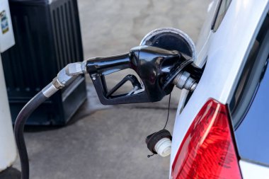 Benzin deposunda gaz hortumu olan beyaz bir arabanın yatay yakın çekim görüntüsü..