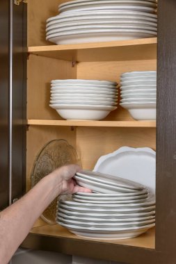 Bulaşık makinesini dolduran bir kadının dikey görüntüsü..