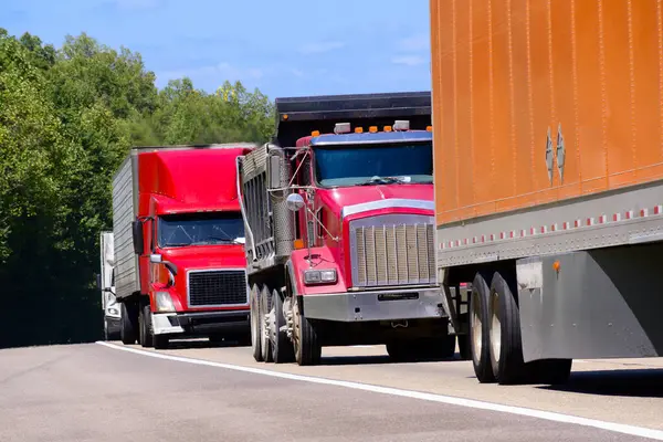 stock image Horizontal shot of a stacked convoy of heavy trucks on the interstate highway. Heat waves rising from the hot asphalt creates a blurring effect on background trucks and foreground pavement.