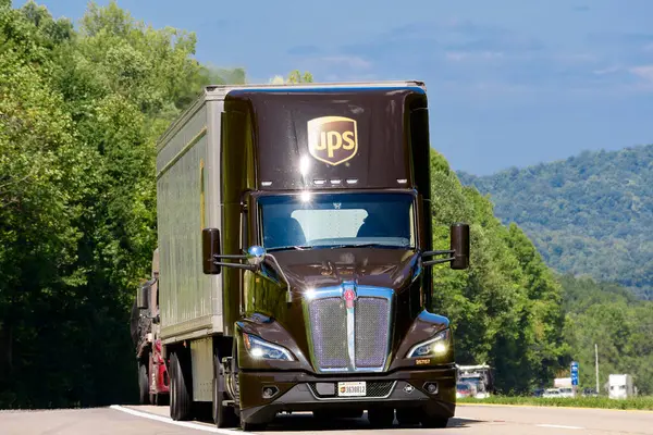 stock image Knoxville, TN, United States  August 20, 2024: horizontal shot of a red eighteen wheeler semi on an interstate highway in the summer heat. Heat waves rising from the hot asphalt creates a blurring effect on background trucks and foreground pavement.