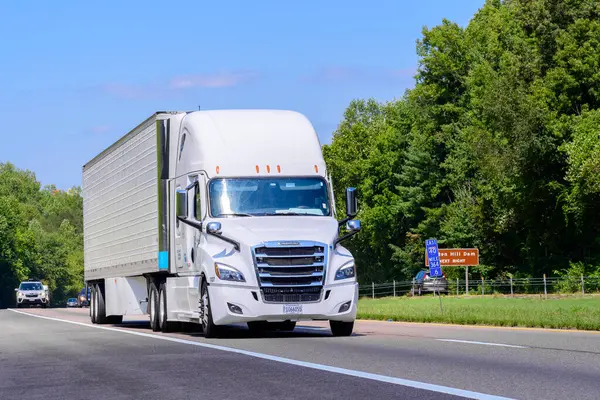 stock image Knoxville, TN, United States  August 20, 2024: horizontal shot of a red eighteen wheeler semi on an interstate highway in the summer heat. Heat waves rising from the hot asphalt creates a blurring effect on background trucks and foreground pavement.