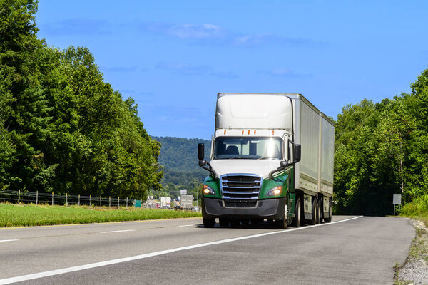 Horizontal shot of a double trailer semi rig climbing an interstate hill near the Smoky Mountains.