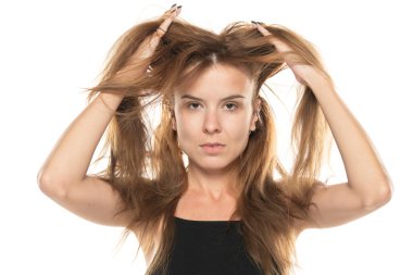 Beyaz stüdyo geçmişinde dağınık, uzun saçlarını gösteren genç bir kadın.