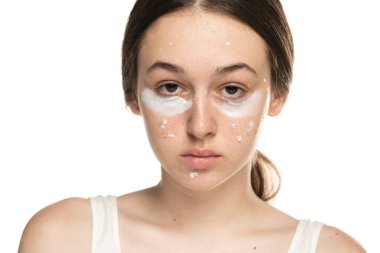 Göz altında kozmetik ürünleri olan genç bir kadının yarım portresi.