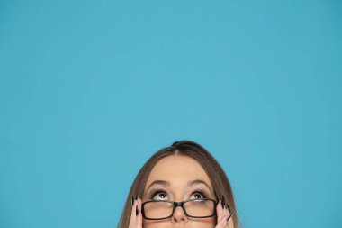 Mavi arka plana bakan gözlüklü genç bir kadının yarım portresi..