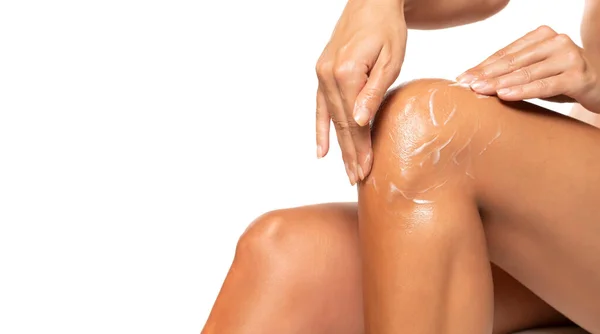 Vrouw Aanbrengen Van Moisturizer Crème Knie Geïsoleerd Witte Achtergrond — Stockfoto