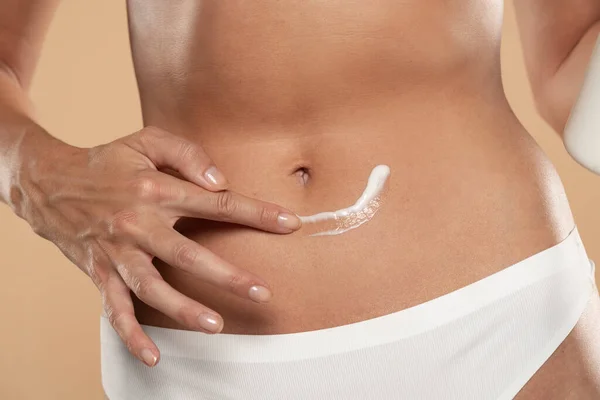 Close Partial View Woman Applying Body Cream Belly Beige Studio — Foto de Stock
