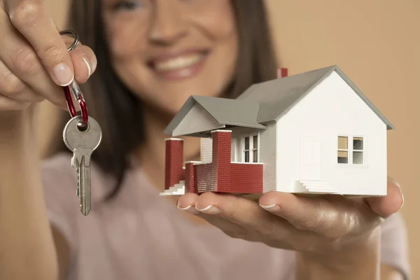 Young Woman Smiling Holding House Sample Model Keys Isolated Beige — Stockfoto
