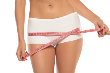 Beyaz stüdyo arka planında kalçalarını ölçen bir kadın. Mükemmel İnce Vücut