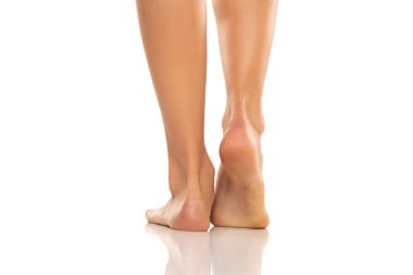Beyaz bir stüdyonun arka planında güzel bakımlı bir kadının çıplak ayaklarının görüntüsü..