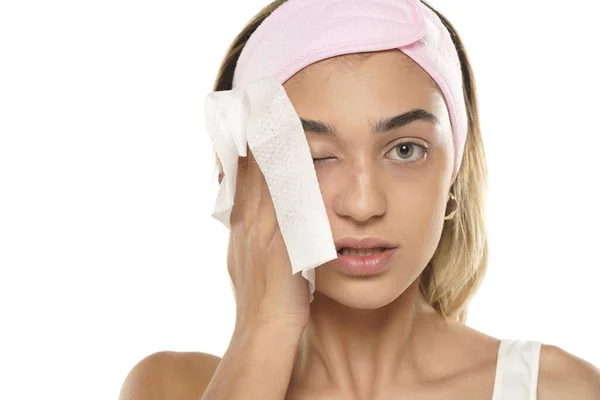 一个迷人的年轻女人在白色的工作室背景上用湿巾擦拭她的脸 — 图库照片