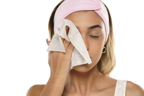 一个迷人的年轻女人在白色的工作室背景上用湿巾擦拭她的脸 — 图库照片