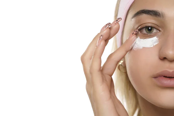 Wanita Muda Cantik Menerapkan Krim Kosmetik Bawah Matanya Pada Latar — Stok Foto