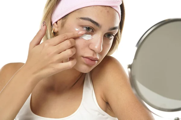 Wanita Muda Cantik Menerapkan Krim Kosmetik Bawah Matanya Pada Latar — Stok Foto