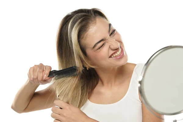 Молодая Нервная Несчастная Женщина Расчесывает Волосы Перед Зеркалом Белом Фоне — стоковое фото