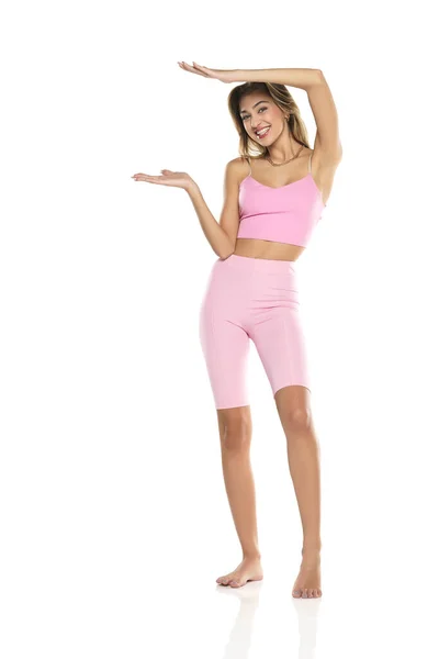 Smiling Woman Pink Leggings Top Presenting Something Her Empty Palm — Stok Foto