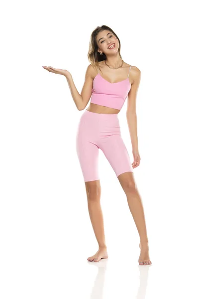 Smiling Woman Pink Leggings Top Presenting Something Her Empty Palm — Stock Photo, Image