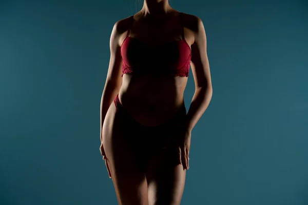 トップフォームで日焼けした女性は 影の中で完璧な体の形 赤い下着 フロントビュー ブルースタジオの背景の女性の体の一部 — ストック写真