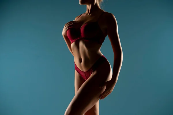 トップフォームで日焼けした女性は 影の中で完璧な体の形 赤い下着 フロントビュー ブルースタジオの背景の女性の体の一部 — ストック写真