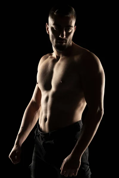 黒のスタジオの背景に影の中に筋肉の無慈悲な男のシルエット — ストック写真