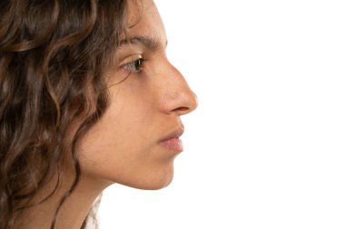 Güzel, ciddi bir genç kadının profil portresi, beyaz stüdyo arka planında kamburu olan bir burun.