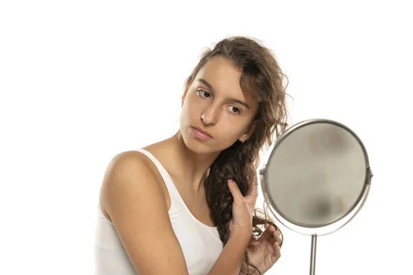 Jovem Verificando Seu Longo Cabelo Ondulado Frente Espelho Fundo Estúdio — Fotografia de Stock