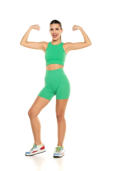 Jovem Desportivo Sorrindo Mulher Shorts Verdes Top Mostrando Bíceps Fundo — Fotografia de Stock