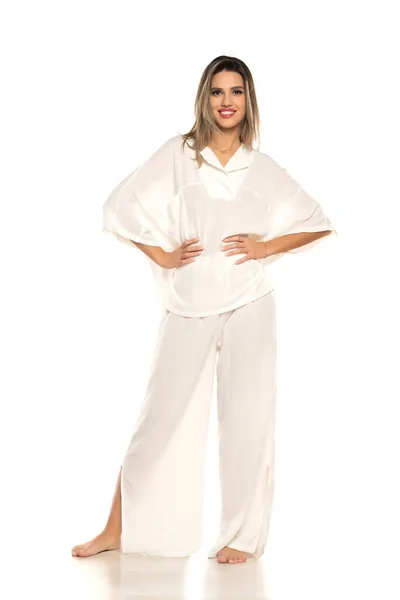 年轻的现代赤脚微笑的女人 穿着白色的裤子和衬衫 摆出白色的工作室背景 — 图库照片