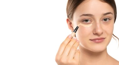 Kusursuz cildine kapatıcı süren, makyaj yapan bir kadın. Kız göz altına düzeltici koymuş. Güzel yüz, cilt bakımı.