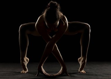 Yoga yapan genç bir kadının sanat silueti. Siyah stüdyo arka planında yoga pozu.