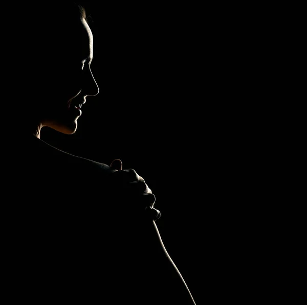 黒いスタジオの背景にバックライトで美しい笑顔の女性の官能的なポートレートシルエット — ストック写真
