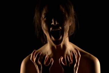 Siyah stüdyo arka planında bağıran mutsuz genç bir kadının silueti.