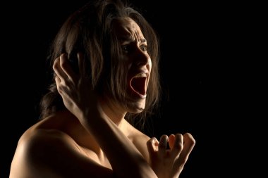 Silhouette of young unhappy screaming woman on black studio background clipart