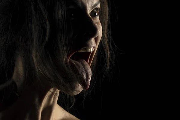 面白い顔をした女性のシルエット 誰かが影のダークスタジオの背景に舌を突き刺す — ストック写真