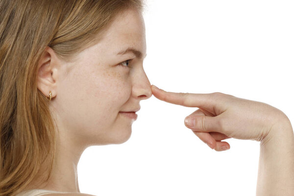 Profile of young woman touching her nose on a white studio background
