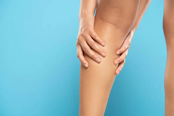 Woman have a calf leg pain and muscle leg pain, Healthcare concept on a blue studio background