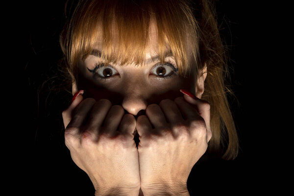 Портрет напуганной молодой женщины чего-то в темноте