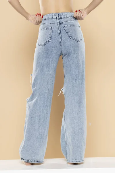 Beine Einer Frau Zerrissenen Jeans Auf Beigem Studiohintergrund Rückseite Rückseite — Stockfoto