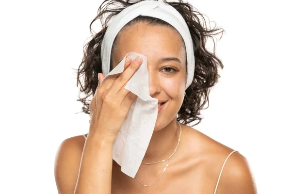 一个年轻的黑发女人用湿湿的湿巾洗脸的画像 女孩正在去除在白色工作室背景下分离的面部组织的化妆品 美容美发概念 — 图库照片